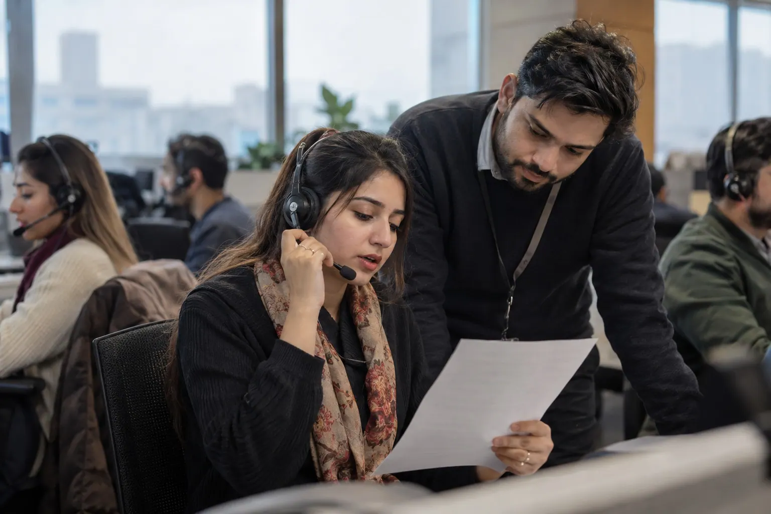 A call-center representative confirms a customer order by phone while a supervisor reviews the order details.