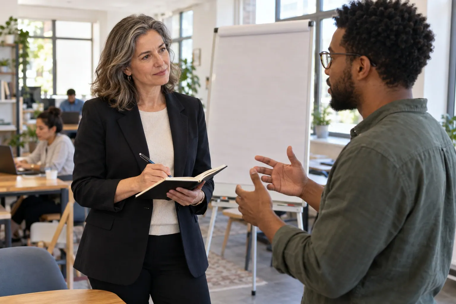 A consultant and client discuss project options beside a planning board.