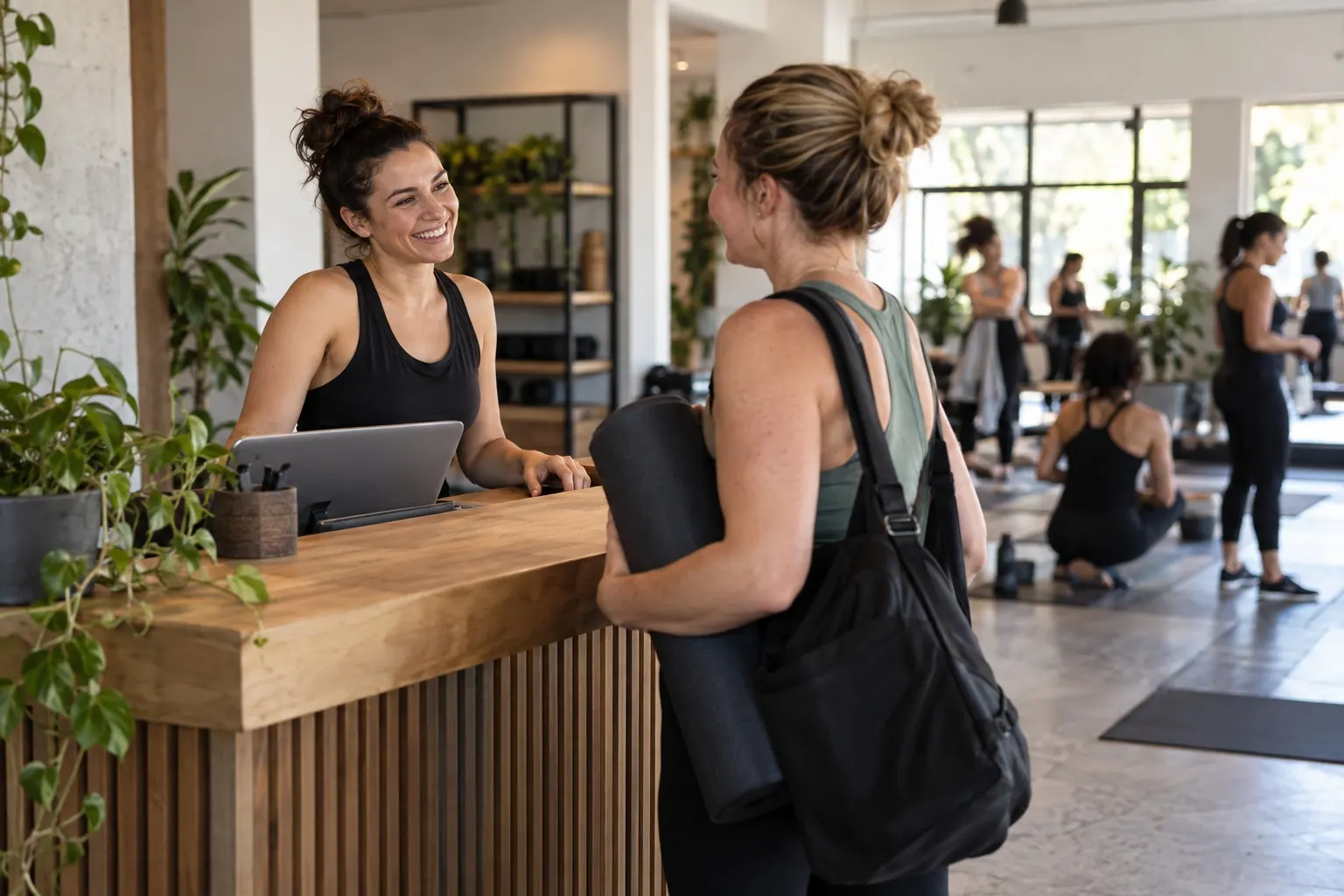 A wellness studio host greets a returning member at the reception counter.